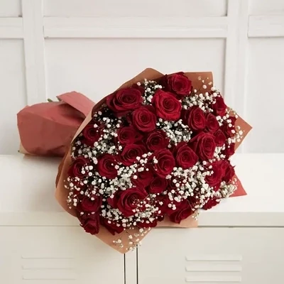 Red roses with gypsophila are used in the bouquet.