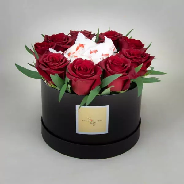 Композиция в коробке состоит из красных роз и рафаэлло.