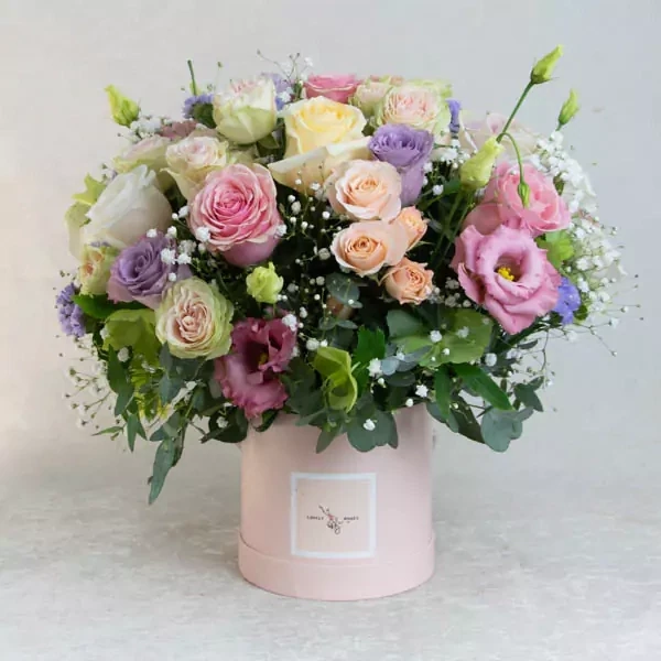 The composition in a pink round box is made of roses and eustomas. The approximate size of the composition is 23 x 23 cm.
