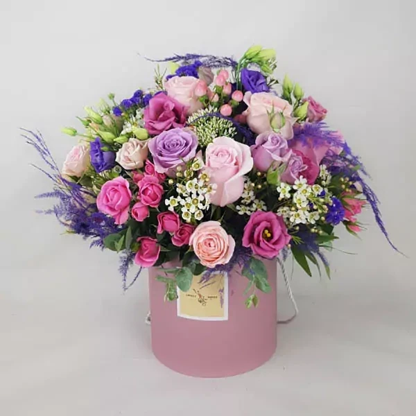 The composition is made with roses and asparagus in purple and pink tones.
