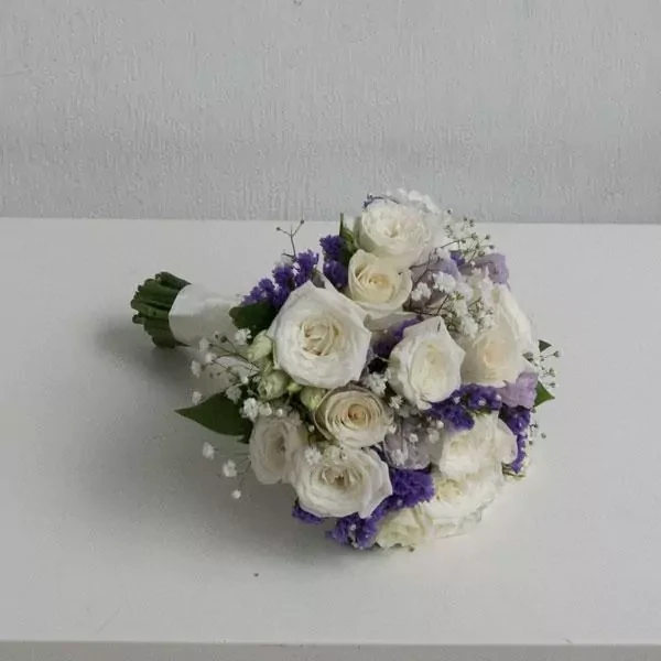 The wedding bouquet is made in soft colors, with roses, eustomas, and statice