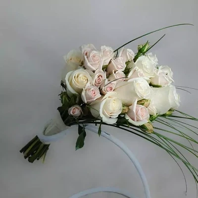 Свадебный букет изготовлен из белых роз и кустовых роз.