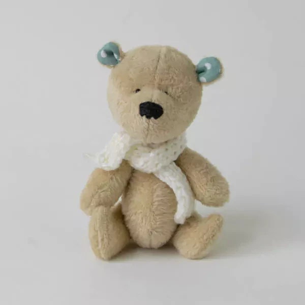 Small handmade teddy in a white scarf