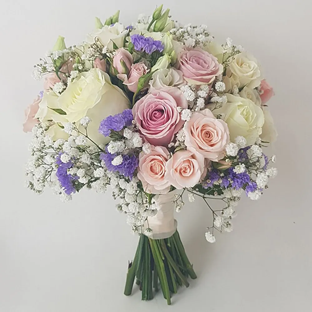 The wedding bouquet is made with pink and white roses and purple supporting flowers