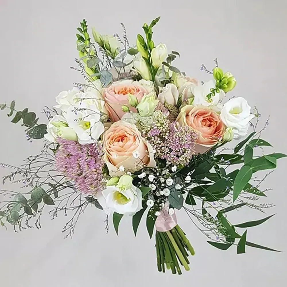 A wedding bouquet in a tousled style made of cream, peach and white roses