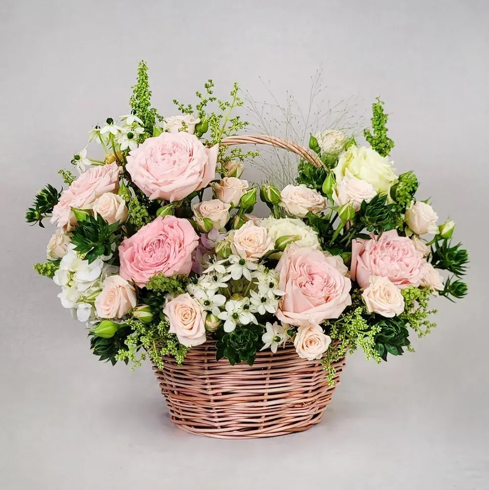 Flower arrangement with delicate roses in a small basket