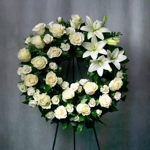 A large funeral wreath with white lilies, frame support, and a funeral ribbon. The average diameter…