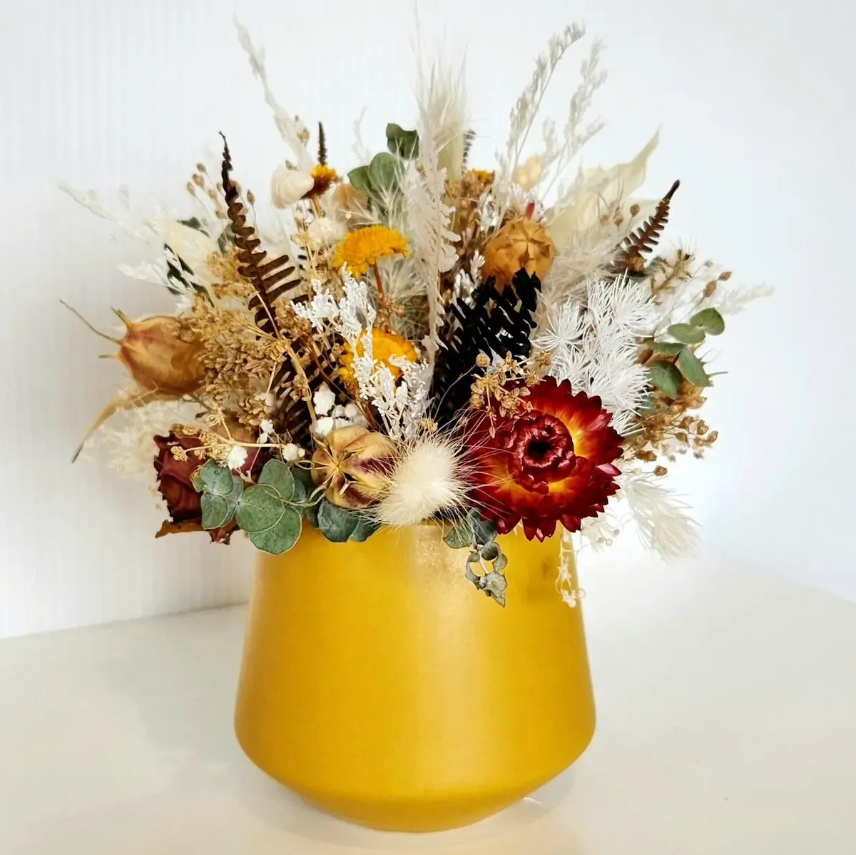 Side view of the Butterscotch dried floral arrangement highlighting its autumnal colours and textures.