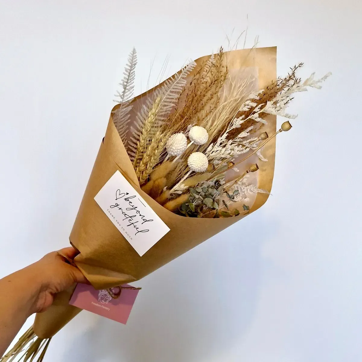 Neutral toned dried bouquet featuring hydrangea, bunny tails, billy buttons, wheat and soft preserved foliage.