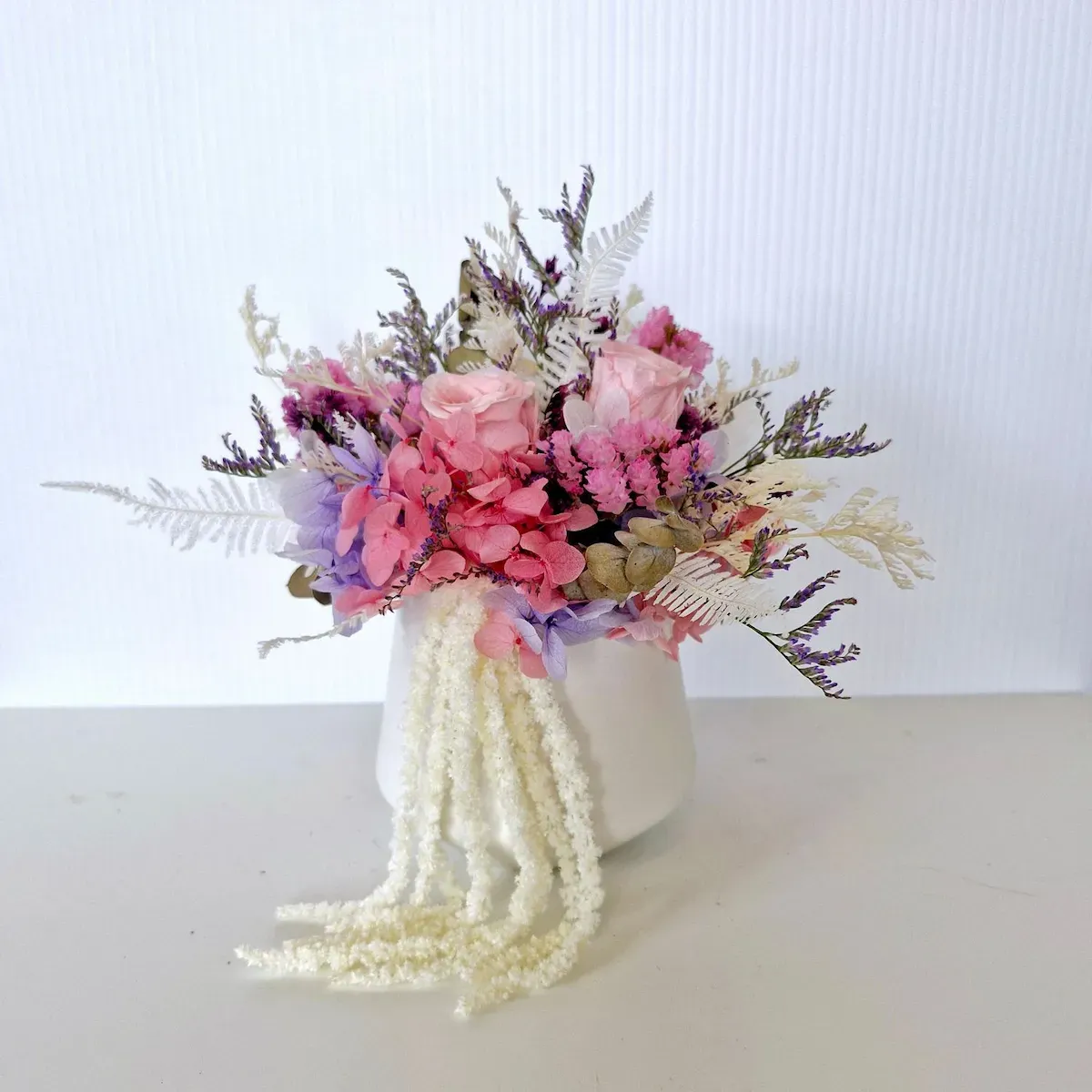 Elegant dried floral arrangement in white ceramic pot, perfect for brightening a home or office.