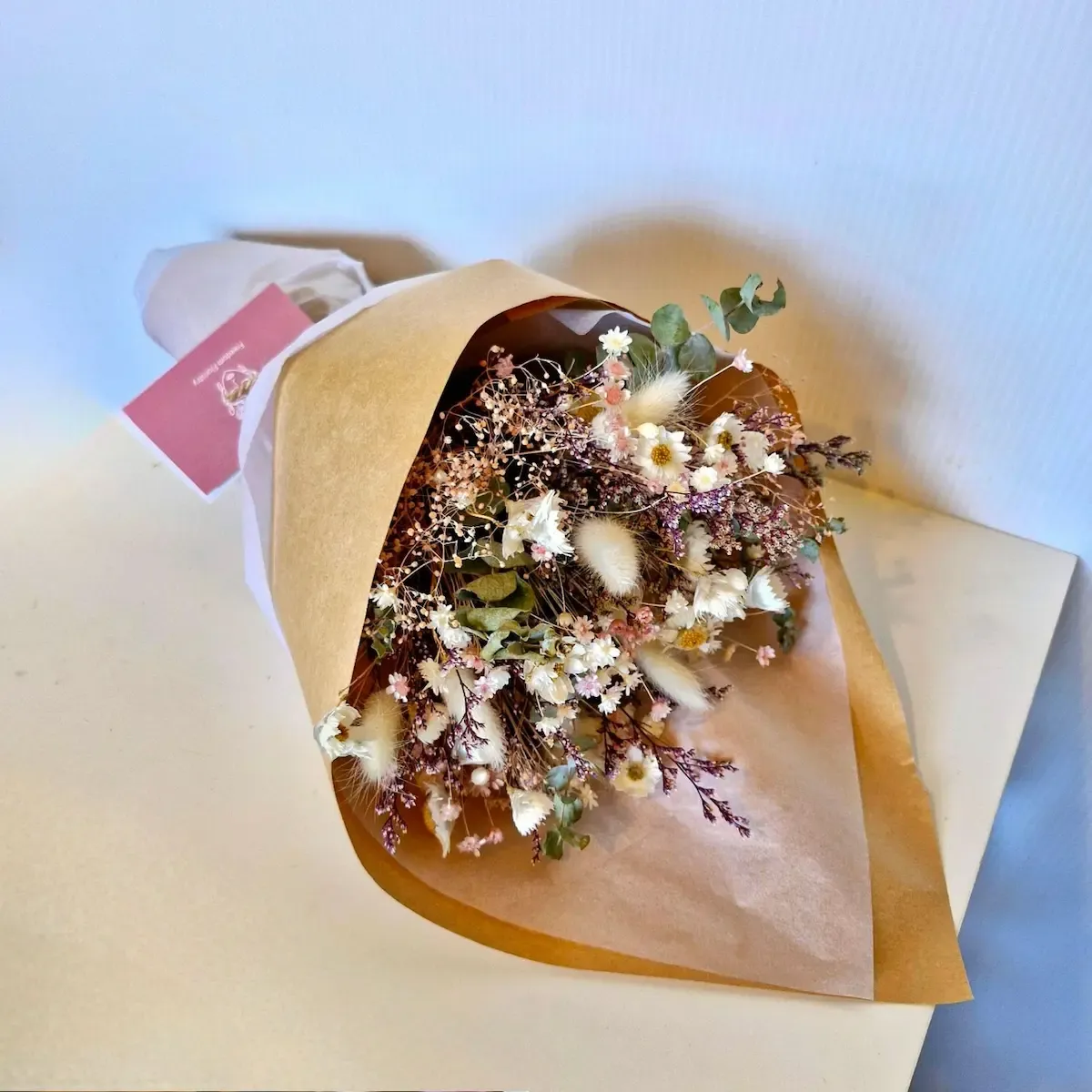 Blush dried floral bouquet in pastel tones displayed laying down with preserved flowers and soft textures.