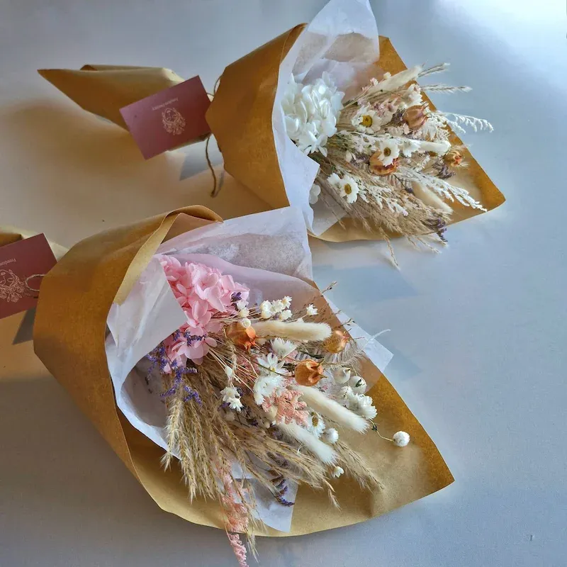 Two Delicate dried floral bouquets lying down, showing pink and white colour options with mixed dried flowers.