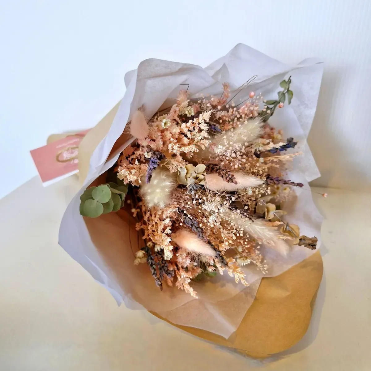 Angelic dried flower bouquet lying down, featuring bunny tails, gypsophilia, lavender, and preserved pastel blooms.