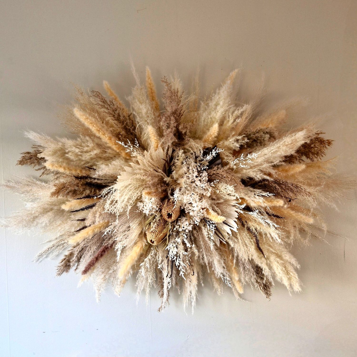 1.2m boho dried floral wall hanging in sandy, creamy tones with textured preserved flowers.