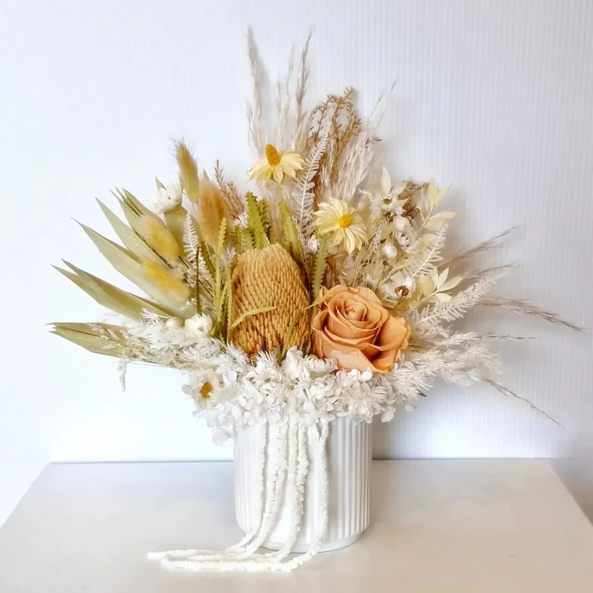 Front view of Angel dried flower arrangement in white ceramic pot with dried daisies, rose, hydrangea, and mixed foliage.