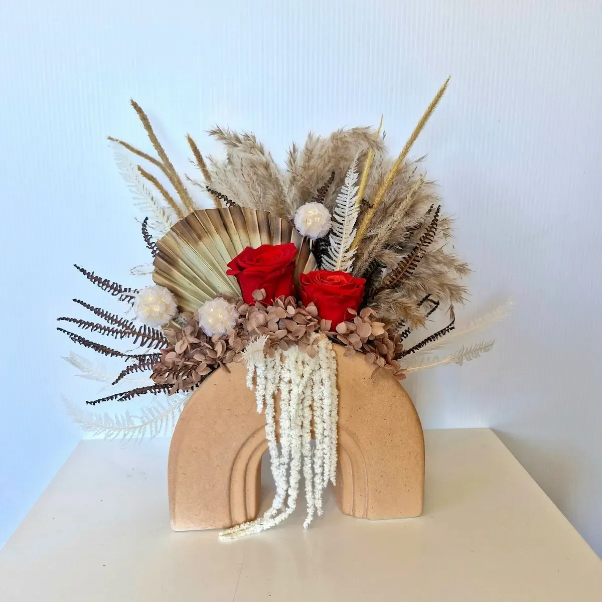 Echo dried floral arrangement with red preserved rose front view in ceramic arch vase with mixed foliage.