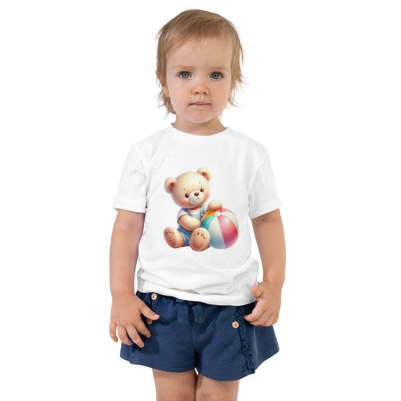 Toddler wearing a white teddy bear and beach ball graphic T-shirt with navy shorts on a clean white background.