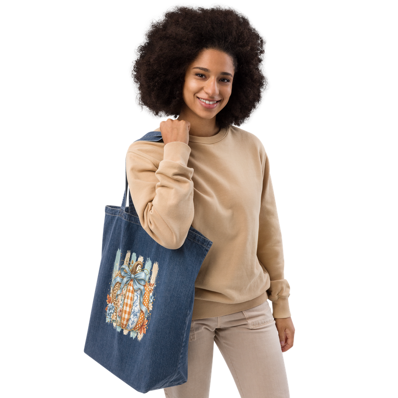 Woman carrying a large blue denim tote with a patchwork pumpkin fall print.