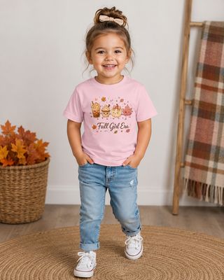 Toddler girl wearing a pink Fall Girl Era T-shirt with autumn drinks, pumpkin, leaves, and cozy fall decor.