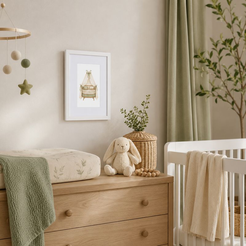 21x30 cm white framed watercolor bassinet art displayed above a changing table in a neutral sage green baby nursery.