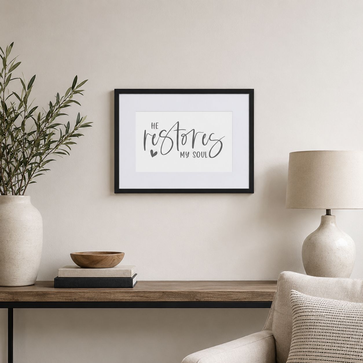 Small black framed “He Restores My Soul” Christian wall art displayed in a bright neutral living room.