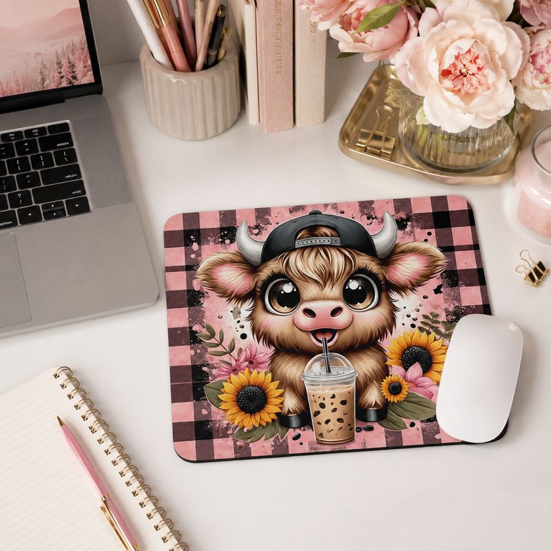 Pink buffalo plaid cow mouse pad on a feminine home office desk with laptop, flowers, notebook, and white mouse.