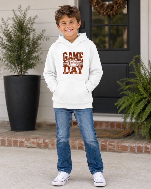 Boy wearing a white kids Game Day football hoodie with distressed rust football design on a front porch.