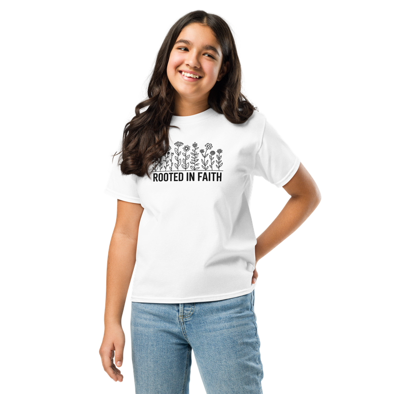 Girl wearing a white Rooted in Faith youth T-shirt with black floral design and blue jeans.