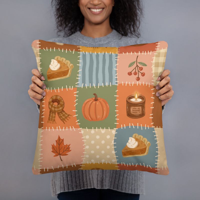 Smiling woman holding an 18 x 18 fall patchwork pillow with pumpkin, pie, scarf, candle, berries, and leaf design.