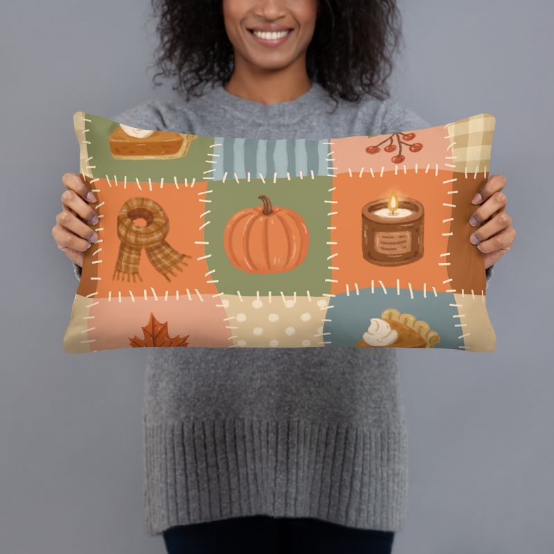 Smiling woman holding a 20 x 12 fall patchwork lumbar pillow with pumpkin, pie, scarf, candle, and leaf design.