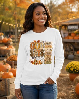 Black woman wearing a white God Says You Are Christian long-sleeve shirt at a fall pumpkin patch.