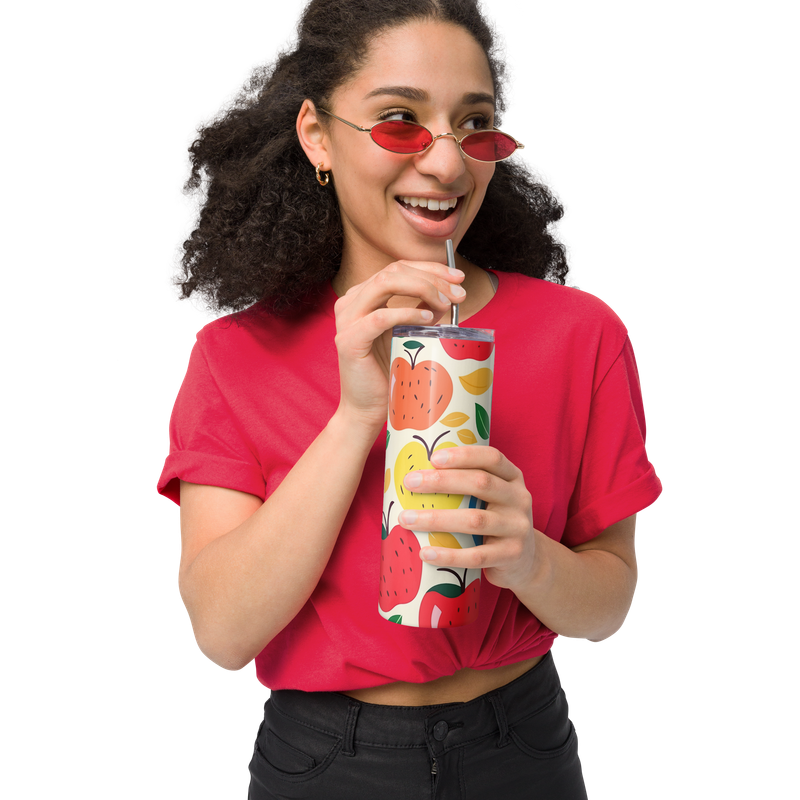 Smiling woman holding the reverse side of a colorful apple tumbler with metal straw.
