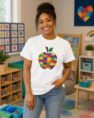 Black teacher wearing a white puzzle apple T-shirt in a sensory-friendly autism classroom.