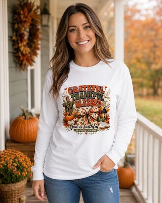 Woman wearing a white Grateful Thankful Blessed Christian fall long-sleeve shirt on an autumn porch.