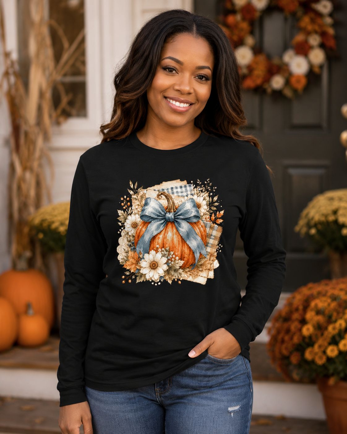 Black woman wearing a black pumpkin bow long sleeve shirt on a porch decorated for fall.