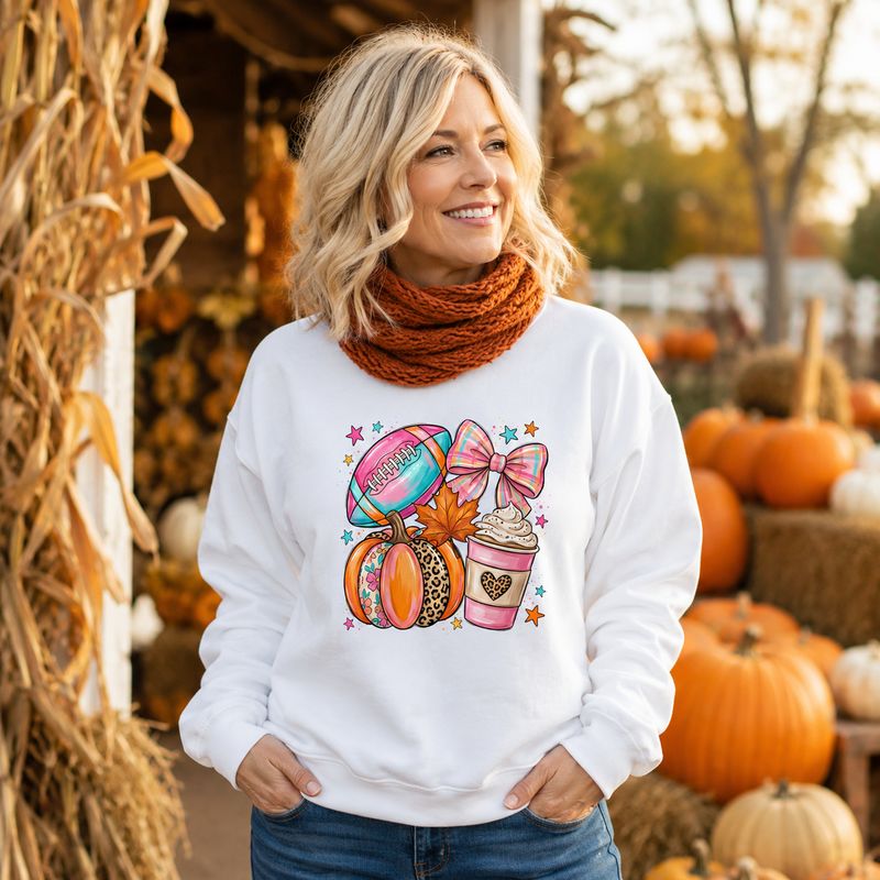 Blonde woman wearing a white football and pumpkin sweatshirt with an orange scarf at a pumpkin patch.