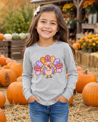 Girl wearing an athletic heather kids long sleeve turkey shirt at a festive pumpkin patch.