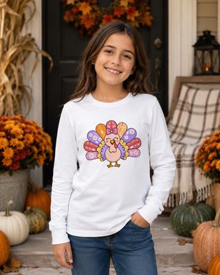 Girl wearing a white kids long sleeve turkey shirt on an autumn porch with pumpkins and mums.