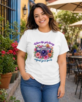 Curvy Latina woman wearing a white floral camera T-shirt with the inspirational “Adjust your focus” photography quote.