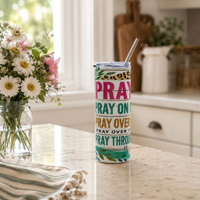 Floral Christian prayer tumbler with teal cross, clear lid, and metal straw on a sunlit kitchen counter.