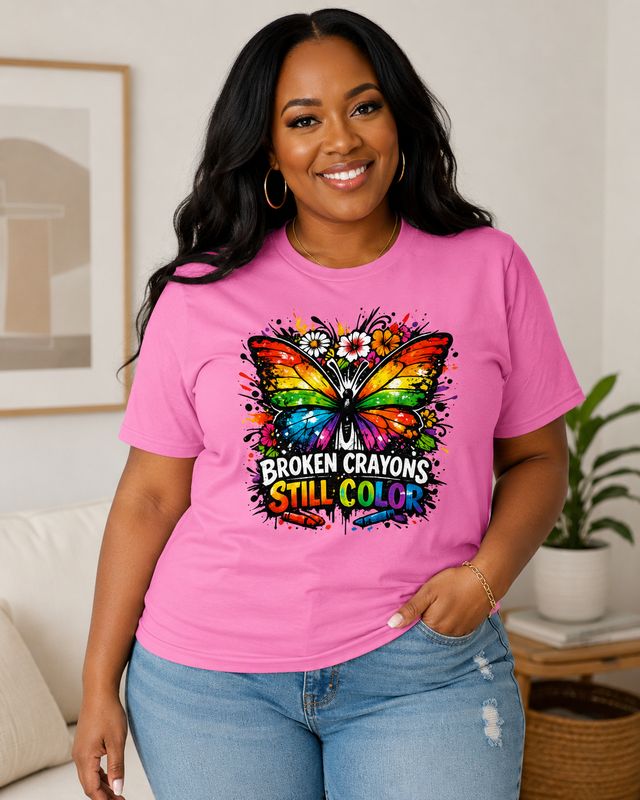 Curvy Black woman wearing an azalea pink Broken Crayons Still Color butterfly graphic T-shirt with jeans.