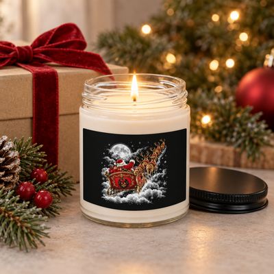 Festive 9 oz Santa Sleigh soy wax candle burning beside a wrapped Christmas present with red ribbon, evergreen branches, and 