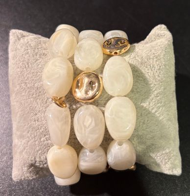 Set van drie armbanden in het crèmekleur afgewerkt met goud