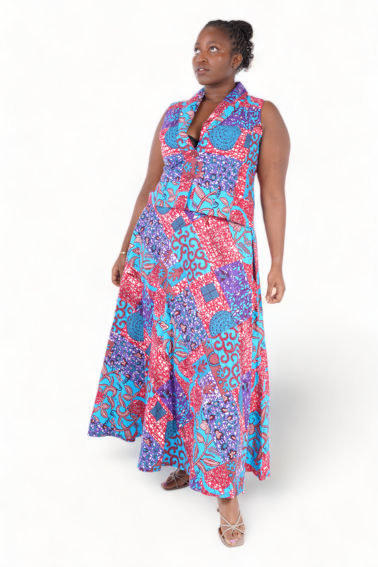 Woman posing in a vibrant, sleeveless patchwork dress featuring red, blue, and purple patterns, exuding confidence and elegance. White background.