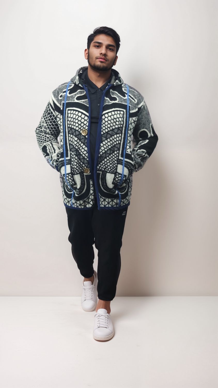 Man in a patterned jacket with geometric designs stands confidently against a light background. He&#39;s in black pants and white sneakers, exuding a casual, stylish vibe.
