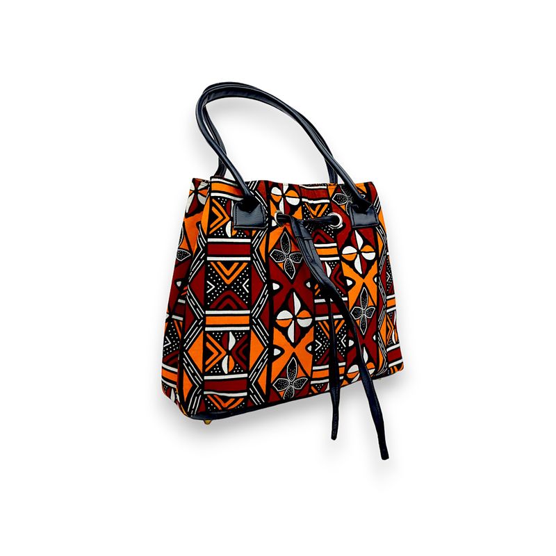 A vibrant handbag with black handles, featuring geometric patterns in orange, red, and black, conveying a bold and ethnic aesthetic.