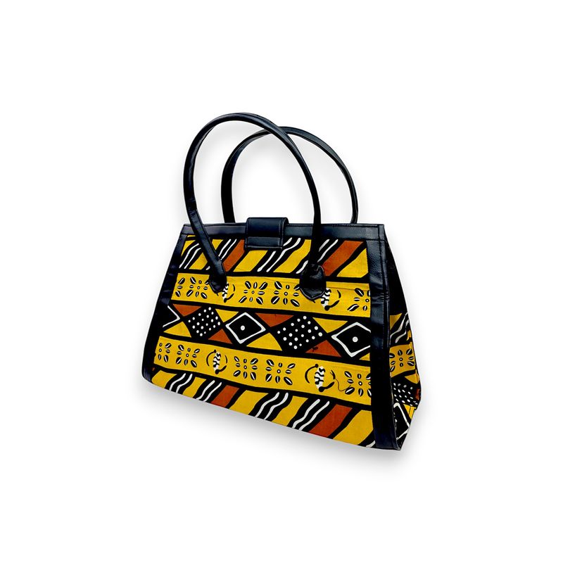 Colorful handbag with black leather handles and trim, featuring vibrant yellow, orange, and black geometric and floral patterns. Energetic and stylish.