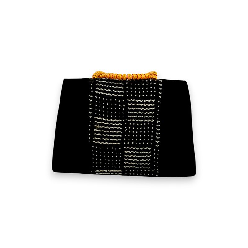 Black handbag with a woven, geometric white pattern. Features a bold orange beaded handle, creating a modern yet traditional aesthetic.