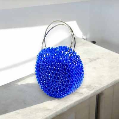 A vibrant blue spherical handbag adorned with sparkling crystals and a silver handle against a black background, conveying elegance and luxury.