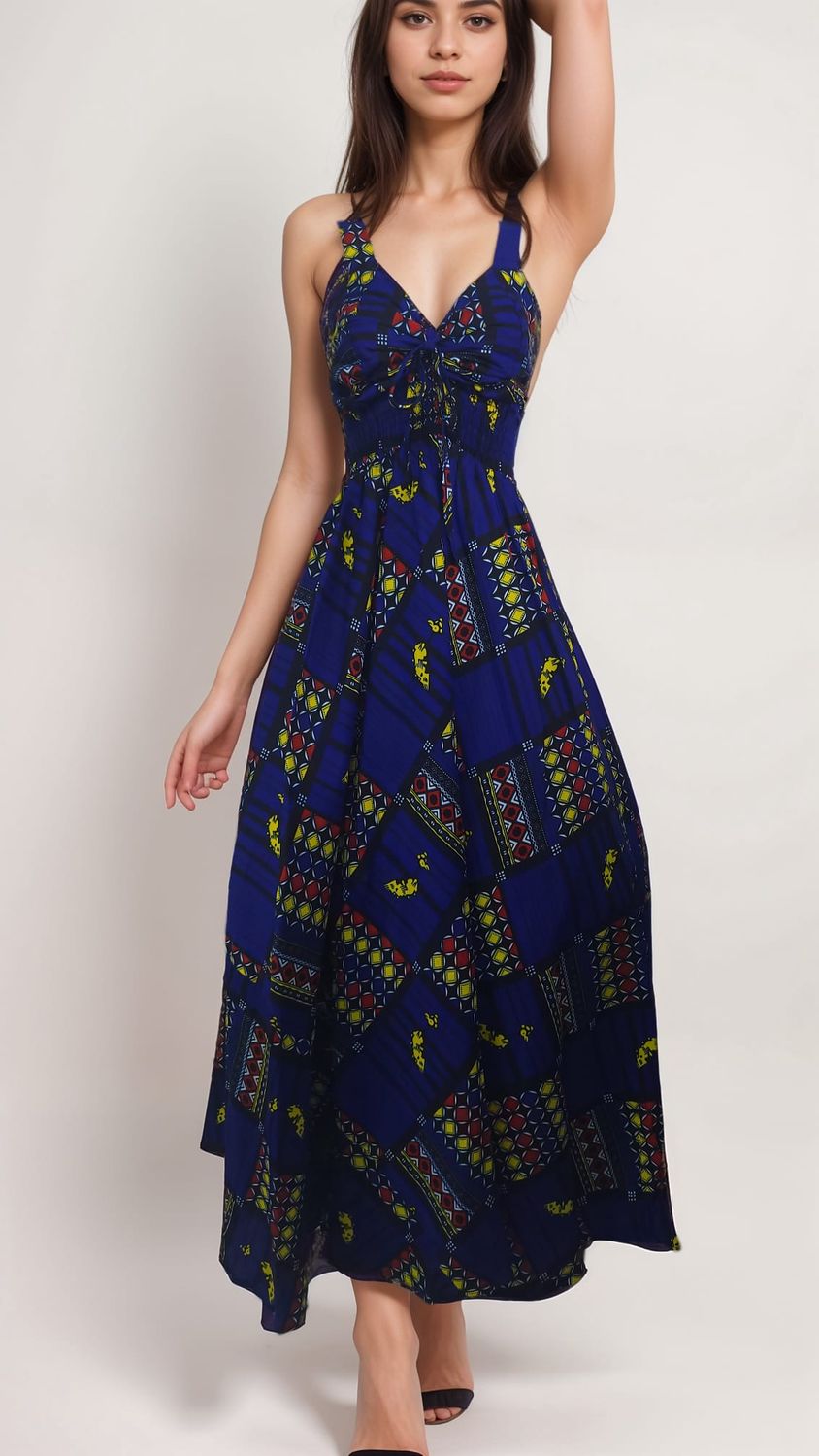 A woman in a vibrant blue maxi dress with colorful geometric patterns stands against a plain background, exuding a calm and confident expression.
